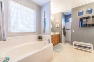 Full bath featuring vanity, a bath, a marble finish shower, and light tile patterned floors
