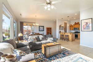 Living area with a ceiling fan, light tile patterned floors, a chandelier, and lofted ceiling