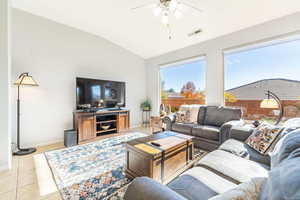 Living area with light tile patterned floors, lofted ceiling, and a ceiling fan