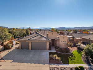 View of front facade with stone siding, stucco siding, driveway, an attached garage, and a mountain view