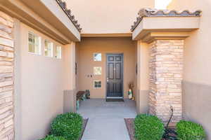 View of exterior entry with stucco siding and stone siding