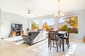 Dining area featuring light tile patterned floors, a ceiling fan, vaulted ceiling, and a chandelier