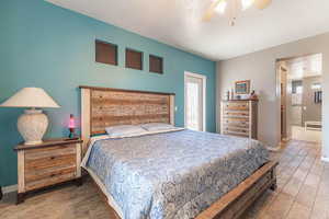 Bedroom with ceiling fan, a textured ceiling, wood finished floors, and ensuite bathroom