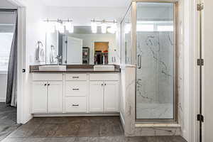 Full bathroom with a spacious closet, double vanity, and a marble finish shower