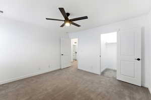 Unfurnished bedroom featuring a walk in closet, carpet flooring, and a ceiling fan