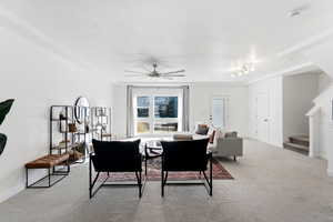 Living room with ceiling fan, carpet flooring, and a textured ceiling