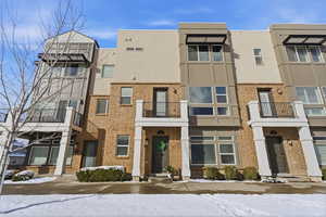 View of front of property with a balcony, stucco siding, and brick siding
