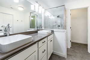 Full bath featuring a marble finish shower and double vanity