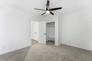 Unfurnished bedroom with light colored carpet, a closet, and a ceiling fan
