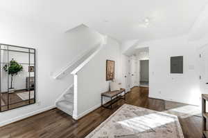 Living room with dark wood finished floors and electric panel
