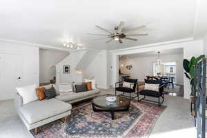 Living room with light colored carpet, a ceiling fan, and hanging lights