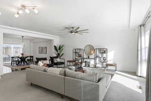 Carpeted living area with ceiling fan and baseboards