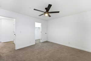 Unfurnished bedroom with a spacious closet, carpet floors, and a ceiling fan