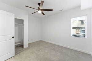 Unfurnished bedroom with light colored carpet, a ceiling fan, and a closet