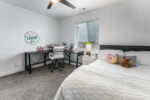 Bedroom featuring light carpet, ceiling fan, and a desk