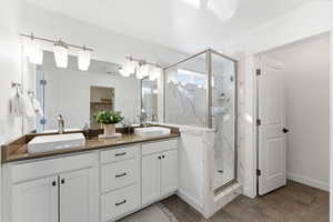 Bathroom featuring double vanity, a marble finish shower, and a spacious closet