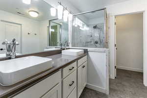 Bathroom featuring double vanity and a marble finish shower