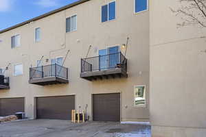 Rear view of property featuring a balcony, a garage, and stucco siding