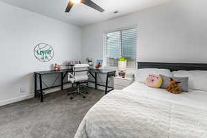 Carpeted bedroom with a ceiling fan and a desk