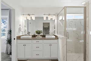 Bathroom with double vanity and a marble finish shower