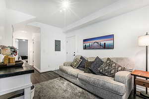 Living area with dark wood-style flooring and electric panel