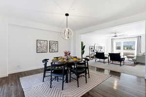 Dining area featuring a ceiling fan, dark wood-type flooring, and a chandelier