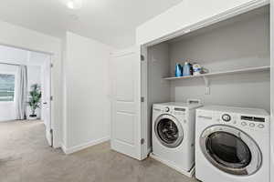 Laundry area featuring light colored carpet and separate washer and dryer