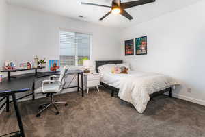 Bedroom with dark colored carpet, an office area, and ceiling fan
