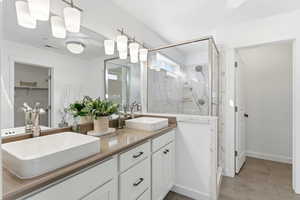 Full bathroom with a marble finish shower, double vanity, and a walk in closet