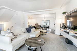 Carpeted living area featuring a chandelier and baseboards
