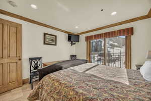 Bedroom with stone tile flooring, access to outside, ornamental molding, and recessed lighting