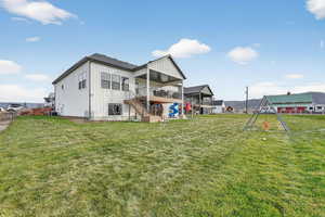 Back of house featuring stairway, a lawn, board and batten siding, and a patio area