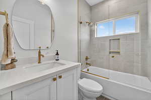 Full bathroom with enclosed tub / shower combo and vanity