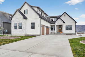 Modern farmhouse featuring board and batten siding, driveway, and stone siding