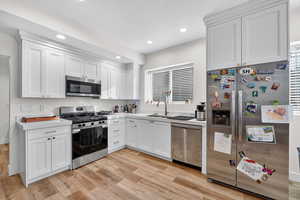 2nd Kitchen with stainless steel appliances, light countertops, white cabinets, light wood-type flooring, and recessed lighting