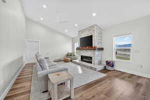 Living area with a fireplace, wood finished floors, recessed lighting, a ceiling fan, and high vaulted ceiling