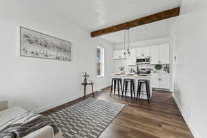 Living room with dark wood-style flooring, beamed ceiling, and recessed lighting