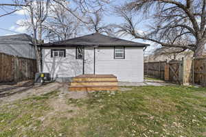 Back of property with a fenced backyard, a gate, and roof with shingles