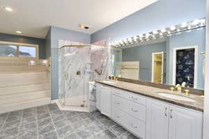 Primary suite bath with double vanity, a marble finish shower, and a spacious closet