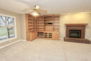 Family room with a brick fireplace, light carpet, and ceiling fan