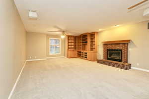 Family room with a brick fireplace, light carpet, and ceiling fan