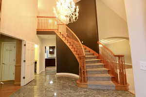 Stairway with marble tiled flooring, a high ceiling, arched walkways, and a chandelier
