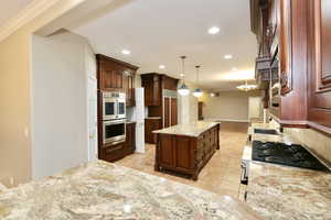 Kitchen featuring decorative light fixtures, stainless steel double oven, light stone countertops, light tile patterned flooring, and recessed lighting