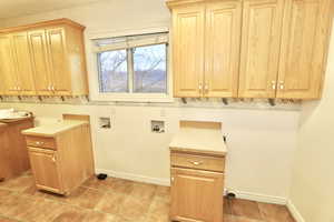 Laundry room for two laundry sets, gas connections,  a sink, light tile  flooring and ample cabinet space