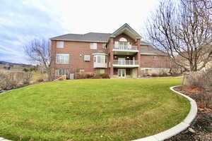 Back of house with brick siding, a lawn, a balcony, and french doors