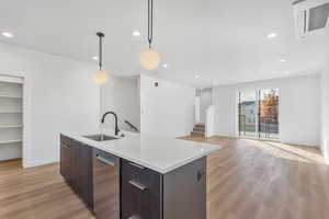 Kitchen featuring dark brown cabinetry, modern cabinets, hanging light fixtures, open floor plan, and light wood-style flooring
