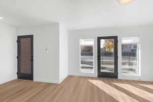 Spare room featuring light wood-style flooring and baseboards