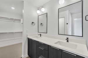Bathroom featuring a spacious closet, double vanity, light colored carpet, and recessed lighting