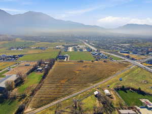 Aerial overview of property's location featuring rows of crops, a mountain backdrop, and rural landscape