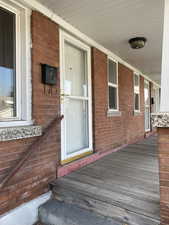 View of exterior entry with brick siding and covered porch